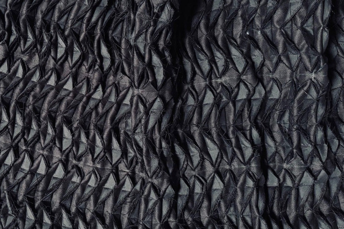 Close-up of textured black fabric on a stone surface